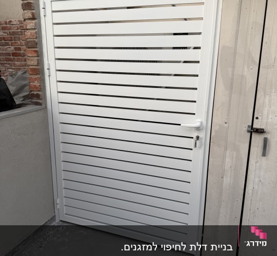 שער אלומיניום לבן מותקן ליד קיר לבנים